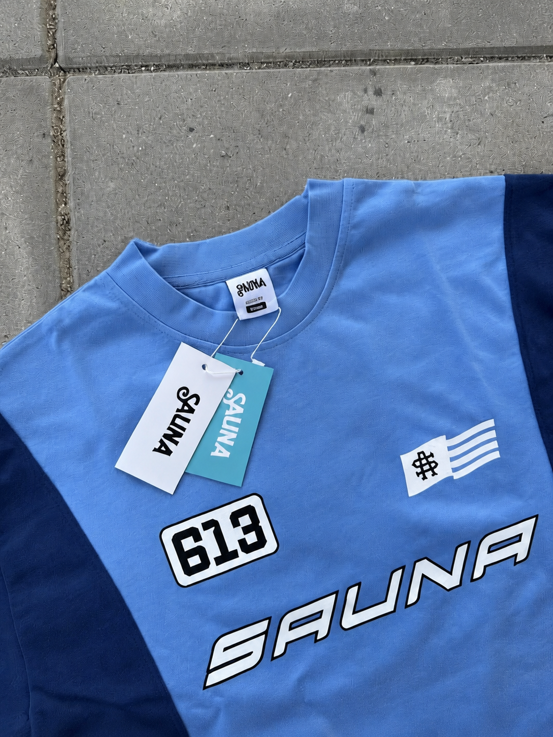 Detaljer og mærker på blå SAUNA T-shirt